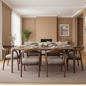 May include: A rectangular wooden dining table with six matching chairs featuring curved backrests and light grey upholstered seats. The table is set with white plates, glassware, and a central floral arrangement, positioned on a large rectangular rug.