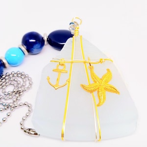 May include: A nautical-themed ceiling fan pull chain featuring a white, sail-shaped pendant with gold-colored anchor and starfish charms. The chain includes blue and turquoise beads and a silver-colored chain.