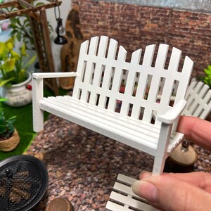 Peut inclure: Banc en bois blanc avec un dossier et un si&egrave;ge de style cl&ocirc;ture &agrave; piquets. Le banc est fait de meubles miniatures pour une maison de poup&eacute;e ou un jardin miniature.