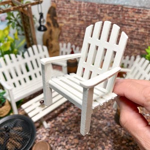 Peut inclure: Chaise longue en bois blanc avec un dossier et un si&egrave;ge &agrave; lattes. La chaise est faite de meubles miniatures pour une maison de poup&eacute;e ou un jardin de f&eacute;es.