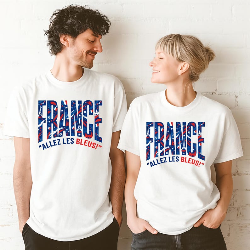 May include: White t-shirts with the word "FRANCE" in blue and red, featuring the Eiffel Tower and stars. The phrase "ALLEZ LES BLEUS!" is printed below the word "FRANCE".
