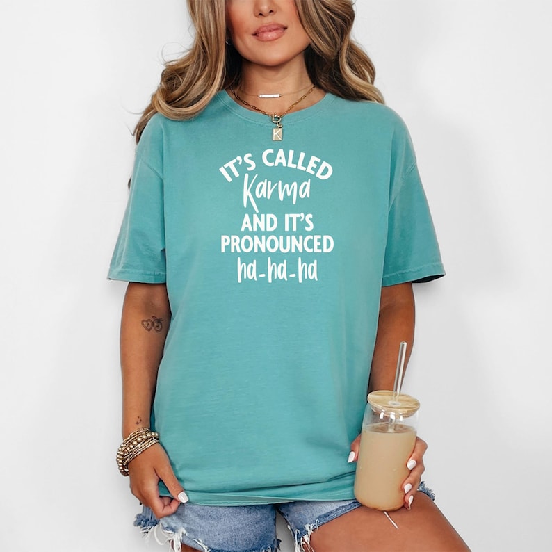 May include: A teal blue t-shirt with the text "It's called Karma and it's pronounced ha-ha-ha" in white.