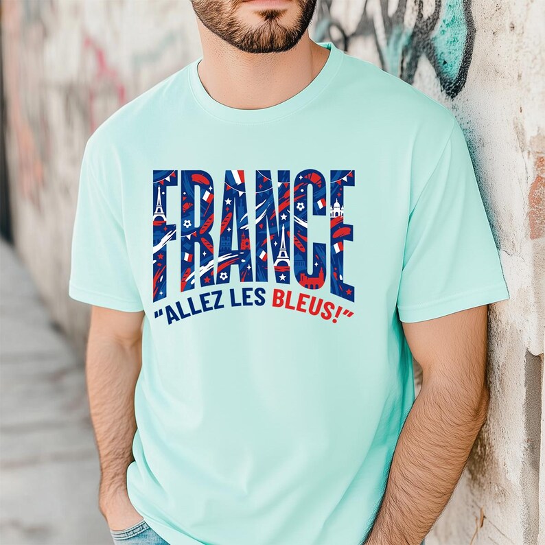 May include: A light blue t-shirt with the word "FRANCE" in a bold, patriotic design. The word is filled with red, white, and blue graphics, including stars and the Eiffel Tower. Below, the phrase "ALLEZ LES BLEUS!" is printed.