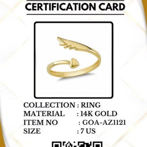 May include: A gold ring with an arrow and wing design, size 7 US, displayed on a certification card. The card includes the text "GOLD OF AMERICA" and "CERTIFICATION CARD". The ring is made of 14K gold.