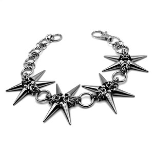 May include: A silver-toned bracelet featuring a series of star-shaped charms with pointed spikes. The bracelet is connected by a chain and a clasp. The design has a punk rock or alternative aesthetic.