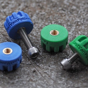 May include: Close-up of four colorful knobs with screws. Two are blue, and two are green. The blue knobs have the text "EastVanPotter" on them. The knobs have a circular design with a gold-colored insert.