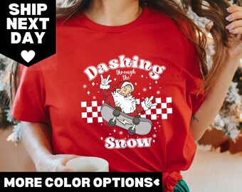 May include: Red t-shirt with a graphic of Santa Claus skateboarding with the text "Dashing through the snow" in a retro font.