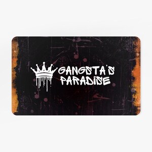 May include: Rectangular card with a distressed black background and an orange and yellow border. The text "GANGSTA'S PARADISE" is written in white, with a white crown graphic above the text.
