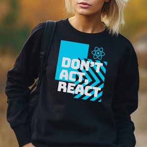 May include: Black sweatshirt with the text "DON'T ACT, REACT" in white and a blue geometric design. The sweatshirt also features a blue atom symbol. The design is centered on the front of the sweatshirt.