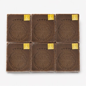 May include: Six rectangular bars of brown Aleppo soap arranged in a grid. Each bar features a circular embossed stamp with the text "TOP 4 ALEPPO SOAP" and Arabic script, accompanied by a small, square, gold-colored sticker in the top corner.