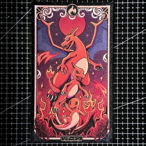 Puede incluir: Una impresión artística rectangular que muestra tres criaturas naranjas tipo dragón en una secuencia de evolución vertical. El fondo es un cielo estrellado púrpura oscuro con un gran sol rojo. Llamas rodean la base y el texto japonés リザードン está en la parte inferior.