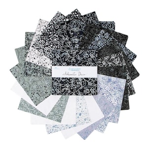 May include: A collection of 12 fat quarter fabric squares in a black and white floral pattern with a subtle gray and blue color variation. The fabric squares are arranged in a fan shape and feature the text "Expressions Achromatic Dance".