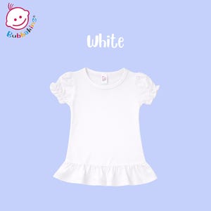 K&ouml;nnte beinhalten: Ein schlichtes wei&szlig;es Kurzarmshirt mit gerafften Puff&auml;rmeln und einem ger&uuml;schten Saum. Das Kleidungsst&uuml;ck hat ein kleines Etikett am Halsausschnitt und der Text White steht &uuml;ber dem Shirt, mit dem Bubbakins-Logo in der Ecke.