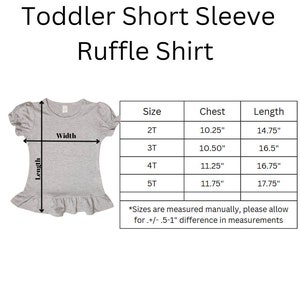 K&ouml;nnte beinhalten: Ein graues kurz&auml;rmeliges R&uuml;schenshirt f&uuml;r Kleinkinder mit einer Gr&ouml;&szlig;entabelle, die Ma&szlig;e in Zoll f&uuml;r die Gr&ouml;&szlig;en 2T bis 5T anzeigt. Die Tabelle enth&auml;lt Spalten f&uuml;r Gr&ouml;&szlig;e, Brustumfang und L&auml;nge sowie einen Hinweis zu Abweichungen.