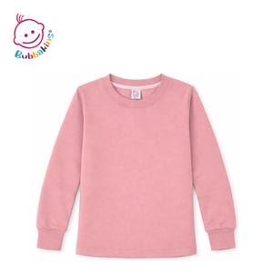 May include: A solid dusty pink long-sleeve shirt with a crew neckline and ribbed cuffs. The interior neck label features the Bubbakins logo, which is also displayed in the upper left corner with the text Bubbakins in colorful letters.