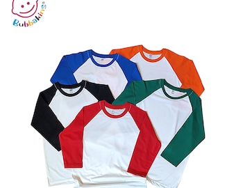 May include: A collection of five long-sleeve raglan shirts featuring white bodies and contrasting sleeves in black, blue, orange, green, and red. Each shirt has a round neckline and the Bubbakins logo is visible in the top left corner.