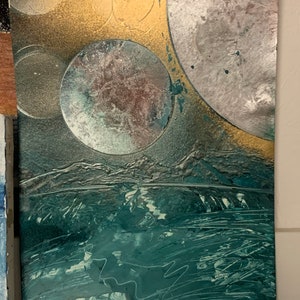 Puede incluir: Pintura abstracta con un aspecto texturizado y en capas. La pintura presenta un fondo verde oscuro con círculos plateados y dorados y un aspecto texturizado y en capas.