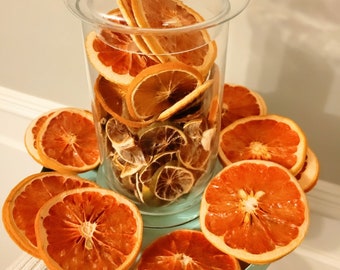 May include: A glass jar with a lid filled with dried orange and lime slices. The jar is sitting on a blue and white plate with more dried orange slices around it.