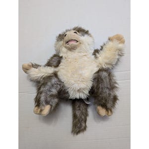 May include: A plush brown and white monkey puppet with a long tail. The monkey has a wide open mouth and a pink tongue.