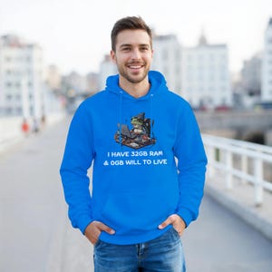 Puede incluir: Sudadera con capucha azul brillante con un diseño de una rana trabajando en un portátil. El texto blanco dice "I HAVE 32GB RAM & 0GB WILL TO LIVE". La sudadera tiene capucha y bolsillo delantero.