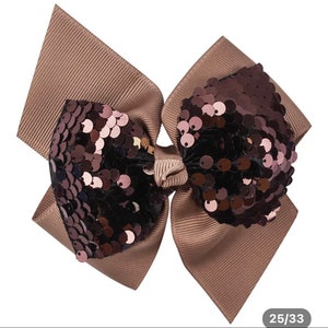 Peut inclure: Un nœud brun avec un grand centre de paillettes irisées scintillantes. Les paillettes sont un mélange de noir, de brun et de rose.