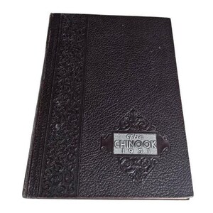 May include: A vintage, dark brown book with a textured cover. The spine features an embossed floral design. The title "The Chinook 1931" is displayed in a silver-colored rectangular emblem on the front cover.