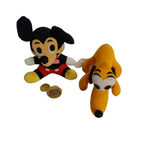 Op de afbeelding: Twee pluche Disney-personages. E&eacute;n is Mickey Mouse, met zwarte oren, een rode en zwarte outfit en gele schoenen. De andere is Pluto, een gele hond met zwarte oren en een wit gezicht. Er is ook een Mickey Mouse-label aanwezig.