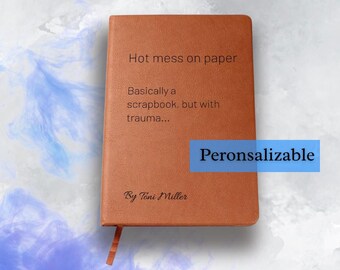 May include: A brown journal with the text "Hot mess on paper" and "Basically a scrapbook, but with trauma..." printed on the cover. The journal has a ribbon bookmark and the word "Peronsalizable" in a blue box.