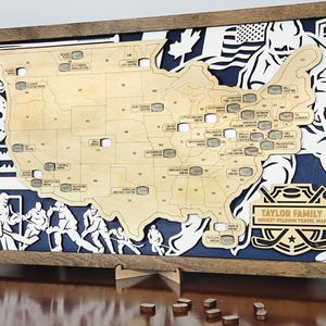 Pu&ograve; includere: Una mappa in legno degli Stati Uniti con gli stadi di hockey contrassegnati da rondelle. La mappa &egrave; incorniciata in una cornice di legno marrone e ha uno sfondo blu. Il testo "TAYLOR FAMILY HOCKEY STADIUM TRAVEL MAP" &egrave; in fondo alla mappa.