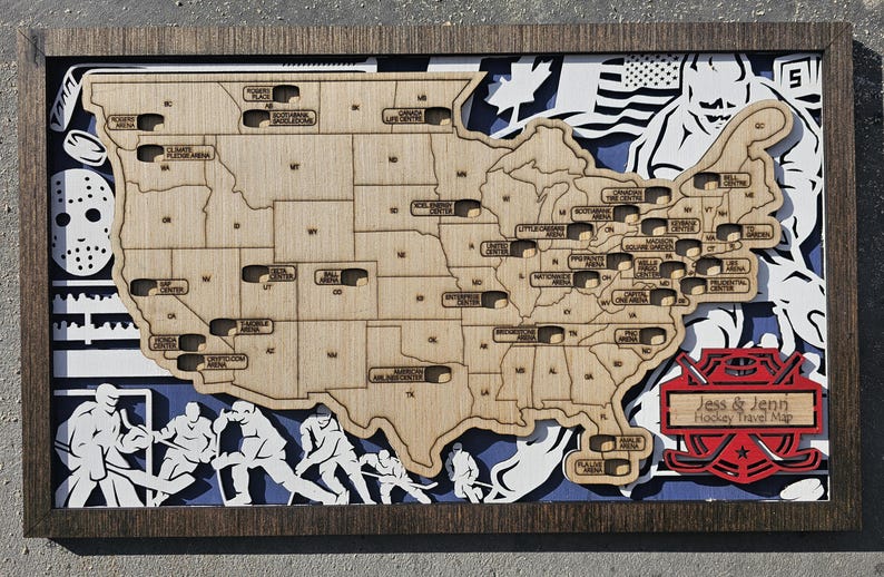 Pu&ograve; includere: Una mappa in legno degli Stati Uniti con gli stadi di hockey segnati. La mappa &egrave; incorniciata in legno scuro e include un logo di bastone da hockey rosso e bianco con il testo "Jess & Jenn Hockey Travel Map".