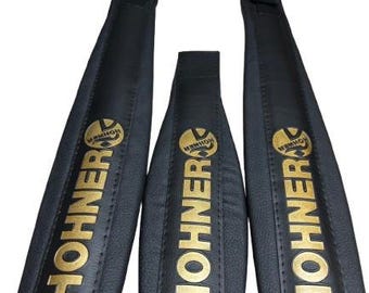 Peut inclure: Trois bretelles d'accordéon noires avec la marque Hohner imprimée en doré verticalement sur chaque pièce. Les bretelles présentent une finition mate lisse avec des bords cousus et des connecteurs en plastique noir en haut de chaque sangle.