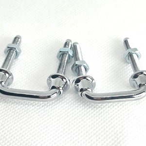May include: Three chrome-plated metal handles with a U-shaped design and threaded screw ends. The handles are designed for attaching to furniture or other objects.