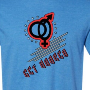 May include: A light blue t-shirt with a graphic design of a stylized male and female symbol with a red heart and the text "GET HOOKED" in red and black.