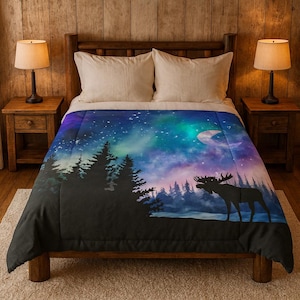 Puede incluir: Un edredón con una escena de bosque nocturno con una silueta de alce, árboles y un cielo estrellado con una luna creciente. La paleta de colores incluye azules, morados y verdes, creando una estética serena y natural.