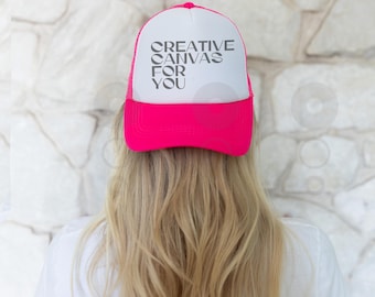 Op de afbeelding: Een roze en witte truckercap met de tekst "CREATIVE CANVAS FOR YOU" op de voorkant.