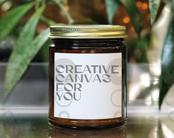 May include: A brown glass candle jar with a gold lid. The label on the jar reads "Creative Canvas For You".