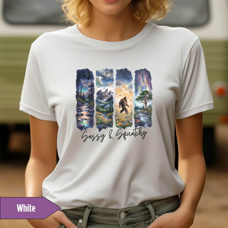 May include: White t-shirt with a graphic of four watercolor scenes featuring a Sasquatch walking through a forest. The text "Sassy & Squatchy" is printed below the graphic.
