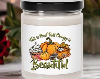 May include: A glass jar candle with a black lid. The label features a fall-themed illustration with a pumpkin, pie, cupcake, and the text "Fall is Proof That Change is Beautiful."