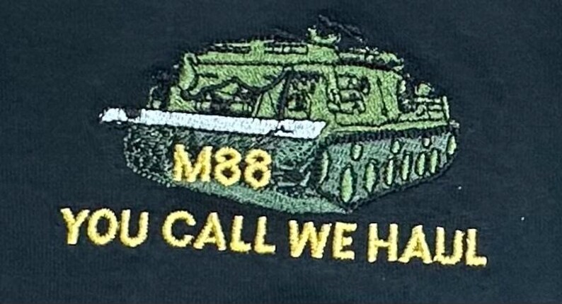 May include: An embroidered patch on a dark fabric featuring a green M88 tank with a white barrel. The text M88 appears in yellow above the tank, and the yellow text YOU CALL WE HAUL is embroidered in a bold font directly underneath the tank graphic.