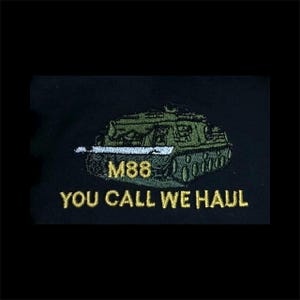 May include: An embroidered patch on a black fabric background featuring a green M88 tank. The text M88 is stitched in yellow thread above the text YOU CALL WE HAUL, which is also embroidered in yellow thread below the tank illustration.