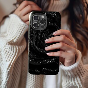 a woman holding up a black phone case