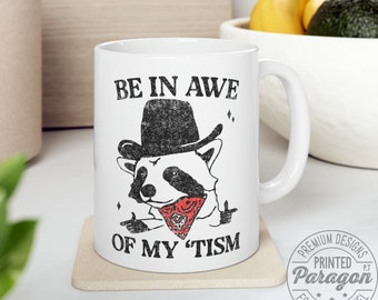 Be in awe of my 'tism, Ceramic mugs C-handle with funny cowboy racoon, available 11oz - 0.33 l and 15oz - 0.44 l