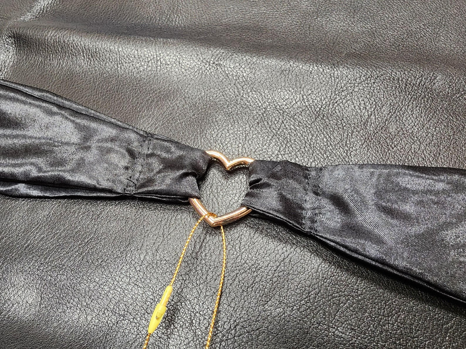 Heart-shaped gold O-ring connecting black silk BDSM ties, perfect bondage restraints for tie-up sex.