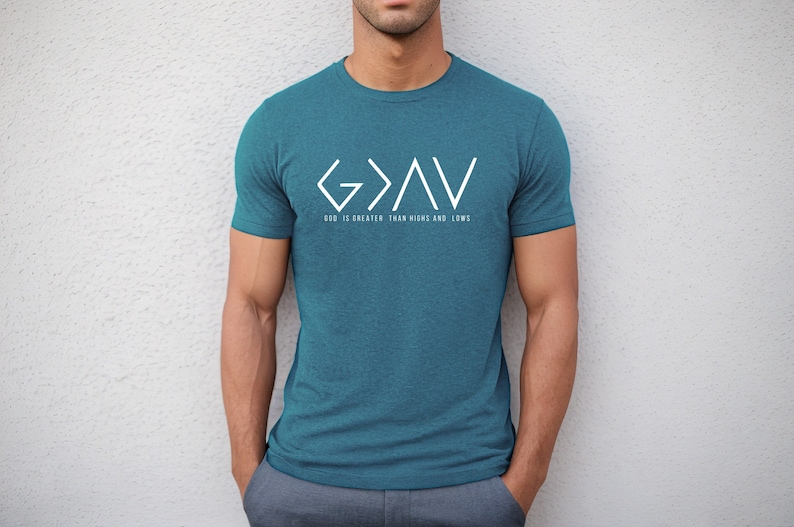 May include: A teal blue t-shirt with a white graphic design of the letters "G>A<V" and the text "God is greater than highs and lows".