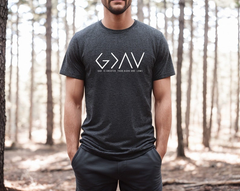 May include: A dark gray t-shirt with a white graphic design that reads "G>A<V" and "God is greater than highs and lows".