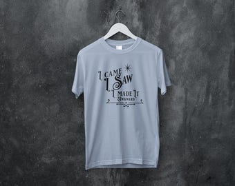 Może przedstawiać: Jasno niebieski t-shirt z czarnym nadrukiem, który brzmi "Przyszedłem, zobaczyłem, zrobiłem to niezręcznie".