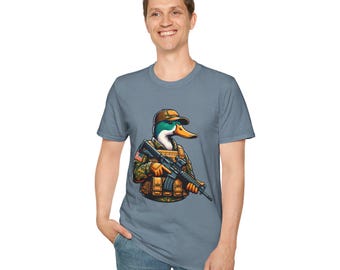May include: A light blue t-shirt with a cartoon duck in military attire, holding a rifle. The duck is wearing a brown cap and camouflage vest. The design includes an American flag patch.