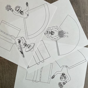 May include: Three printable paper templates featuring black and white illustrations of skeletons dressed in traditional Mexican wedding attire. The skeletons are holding flowers and a guitar.