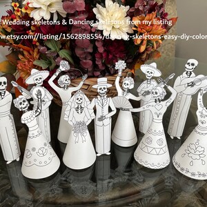 May include: A set of nine paper cut-out skeletons dressed in traditional Mexican wedding and party attire. The skeletons are ready to be coloured. The skeletons are holding musical instruments, flowers, and a fan. The text on the image reads "Wedding skeletons & Dancing skeletons from my listing https://www.etsy.com/listing/1562898554/dancing-skeletons-easy-diy-coloring"
