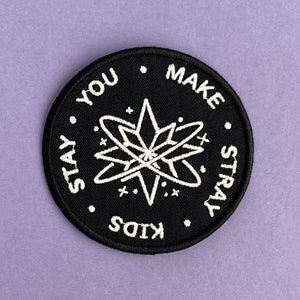 Könnte beinhalten: Schwarz-weiß gestickter Aufnäher mit dem Text "Stay You Make Stray Kids" in einem Kreis um ein stilisiertes Sternburst-Design.